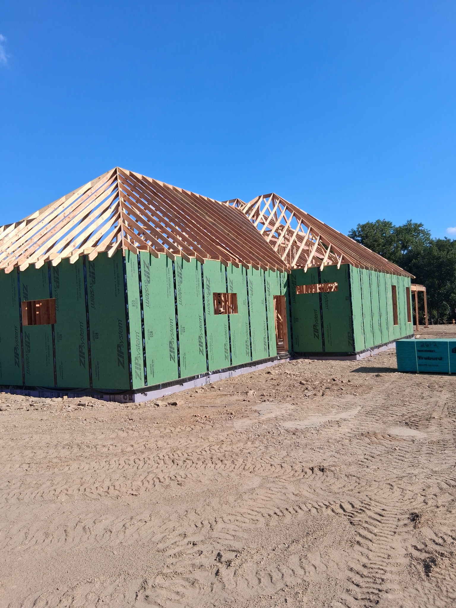 New home wrapped in green sheathing with roof trusses in place