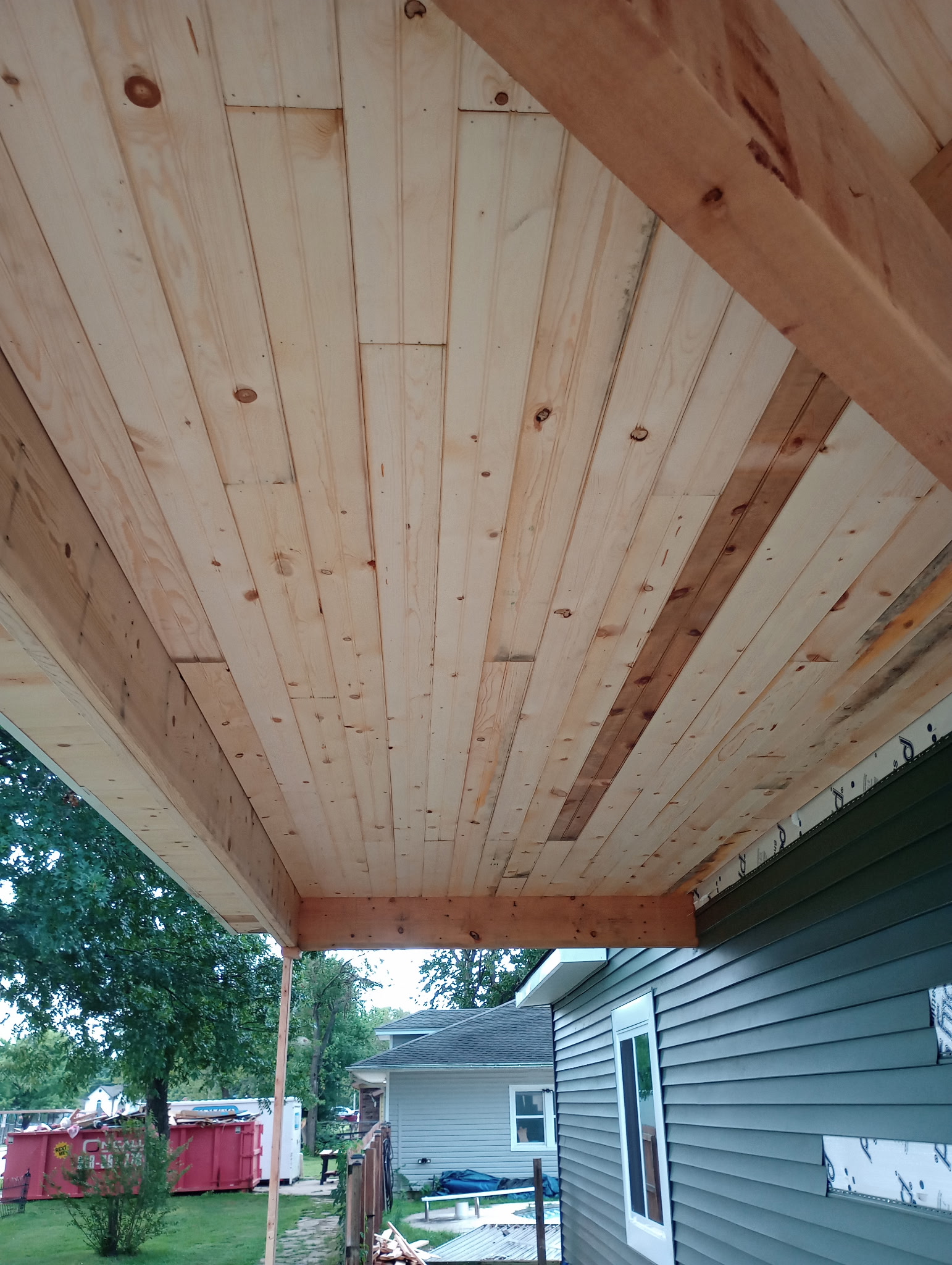 Wood porch ceiling and beam installed along the side of a house