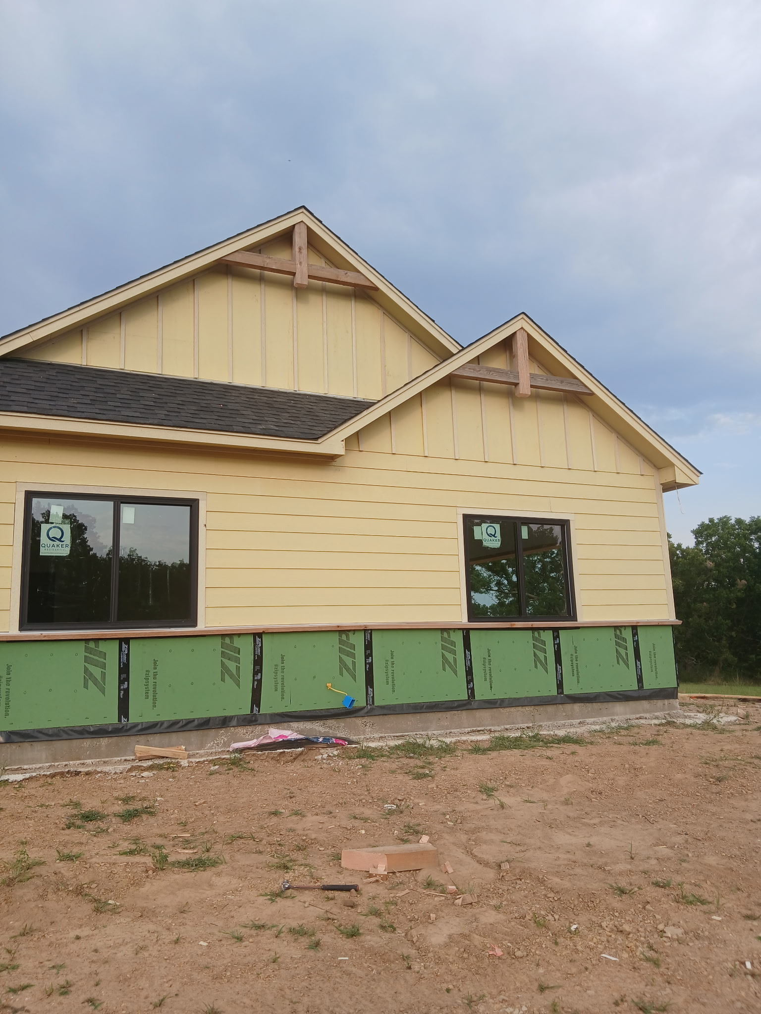 House exterior with yellow siding, timber gable braces, and new windows