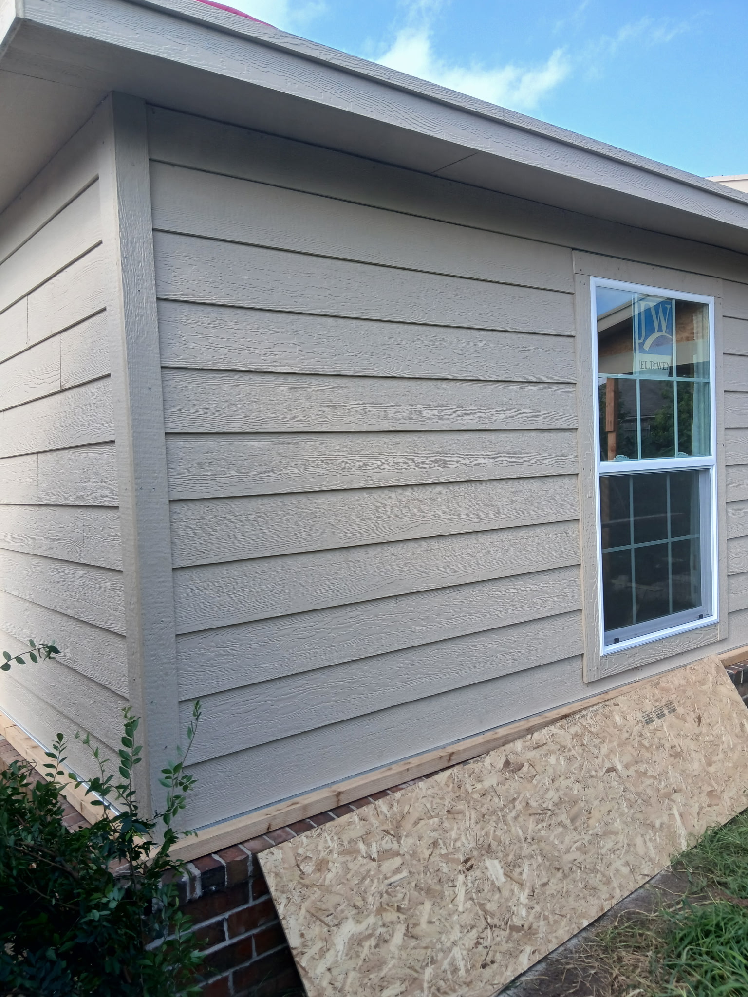 Beige lap siding and a new window installed on a residential wall